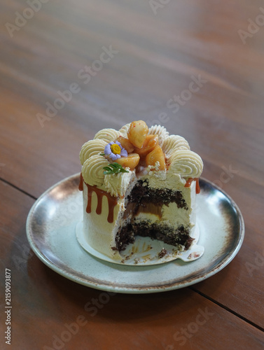 The macadamia coffee cake has been partially eaten on dark brown and white ceramic dish on wooden floor, food, sweet, object, pottery, copy space
