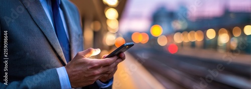 Businessman Using Smartphone on Subway Platform at Dusk