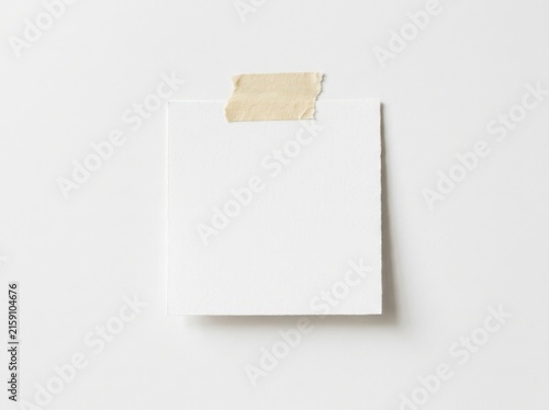 Blank white note paper attached with masking tape isolated on white background