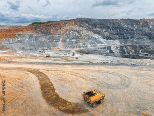 Wide open pit mine with haul truck traversing dirt road