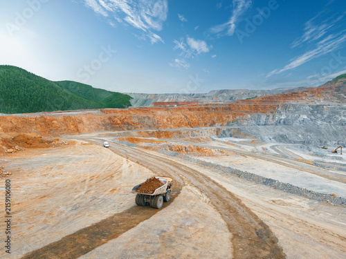 Aerial top view Mining dump truck hauling ore on winding dirt road in open pit mine