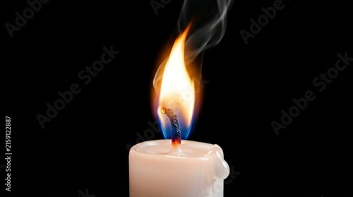Burning candle flame and smoke glowing against a dark background in a moody indoor setting creating a peaceful atmosphere