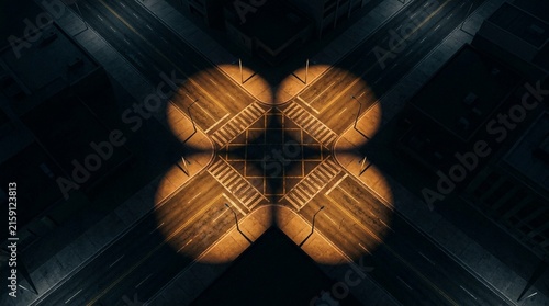 Aerial city intersection street lights illuminate a dark urban crossroad at night creating a glowing clover pattern from a top down view