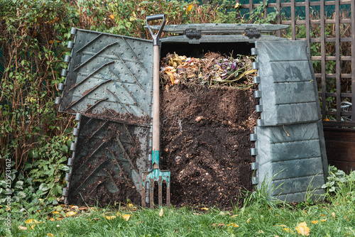 Open compost bin with garden fork leaning against fresh organic waste