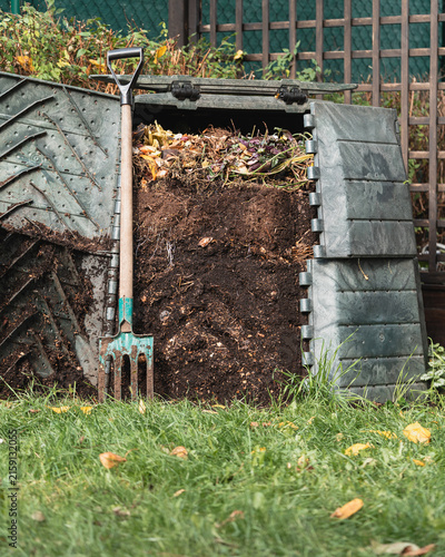 Open compost bin with garden fork leaning against fresh organic waste