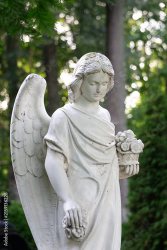 Foto A serene white angel statue holding flowers in a cemetery setting