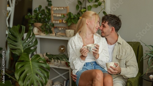Canvastavla Young couple sharing a tender moment with coffee cups surrounded by lush indoor
