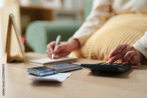 Картината върху платно Person using calculator, smartphone and notebook to calculate household expenses
