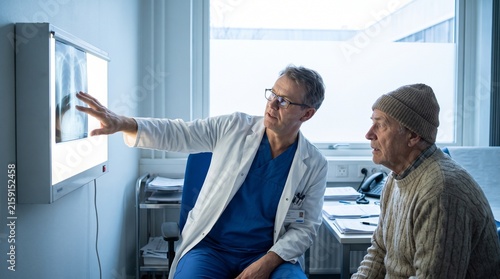 A doctor reviewing an X-ray on a lightbox with a patient, genuine explanatory moment