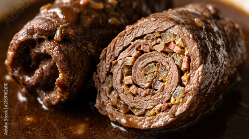 Close-up of savory beef roulades filled with bacon, onions, and spices, served in a rich, dark gravy, a delicious and hearty meal