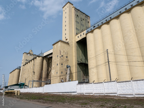 Large concrete grain elevator building against a clear blue sky, industrial agricultural storage facility for grain processing and farming