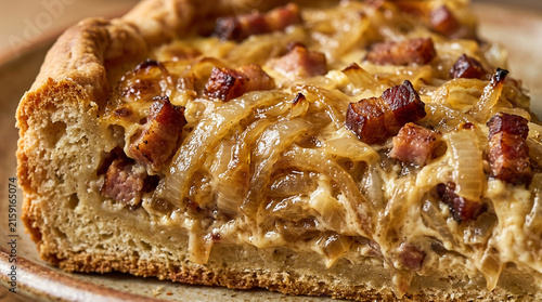 A close-up of a slice of traditional German onion tart, Zwiebelkuchen, filled with caramelized onions and crispy bacon on a flaky crust
