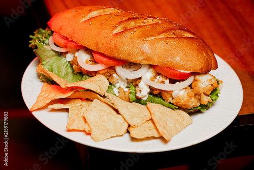 Bild auf Leinwand Large Fried Chicken Sandwich with Tomato Onion and Chips