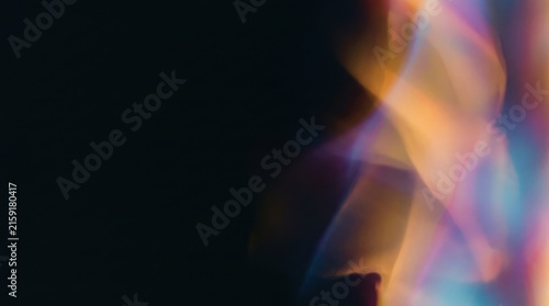 Abstract rainbow light leak glow with soft colorful flares on a dark black background