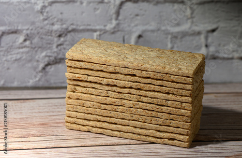 Canvastavla Stack of rectangular crispbread on a wooden surface against a white brick wall