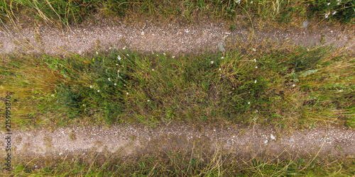 view from above on texture of gravel road among grass field
