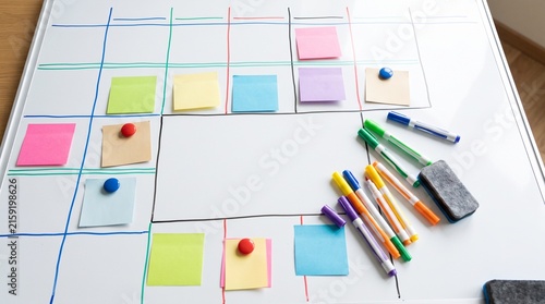 Planning Board with Sticky Notes: A whiteboard is organized with a grid, colorful sticky notes, and markers, suggesting a project management or planning session.