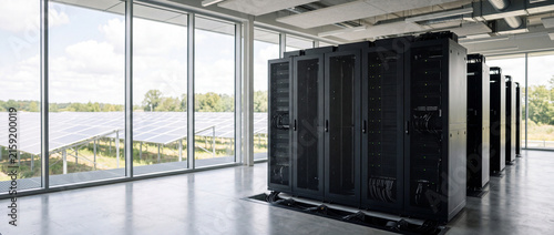 Modern green data center with server racks overlooking solar farm through floor-to-ceiling windows