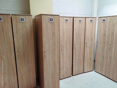 Wooden lockers numbered 31 to 36 arranged in a row inside a bright, modern facility with a clean floor and neutral-colored walls