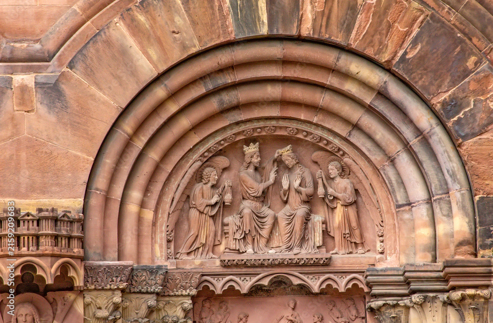 Fototapeta premium Gothic stone relief depicting the Coronation of the Virgin Mary by Christ, surrounded by angels, on the south transept portal of Strasbourg Cathedral in Strasbourg, France.