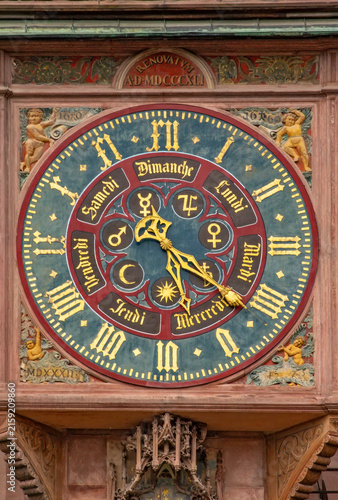 Detailed view of the historic astronomical clock on the facade of Strasbourg Cathedral, featuring an ornate clock face, Roman numerals, zodiac symbols, decorative figures and Gothic stonework.