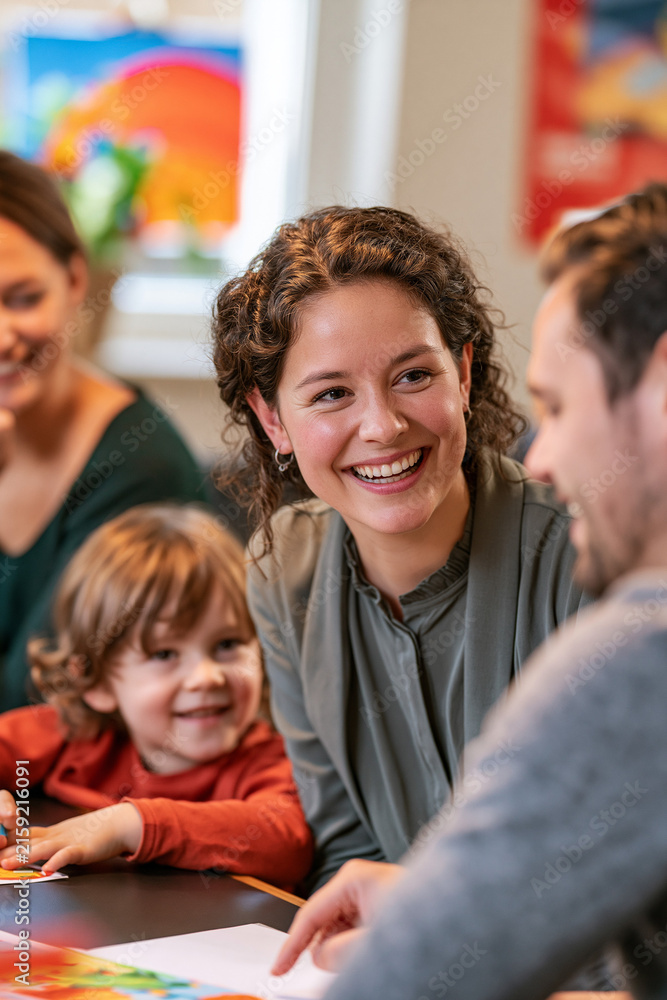 Obraz premium Joyful woman talking with man while child smiles at table