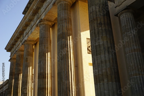 Architectural detail of beautiful golden light casting shadows among the columns of Brandenburger Tor, Berlin, during sunrise in the morning