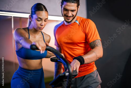 Medium shot of an athletic man and woman smiling and posing together after completing a challenging workout session in a gym.