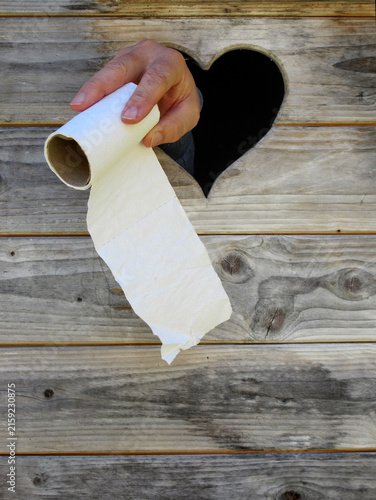 stuhlgang - defecation. hand showing toilet paper through a toilet door window. Hand zeigt Klopapier durch das Fenster einer Toilette.
