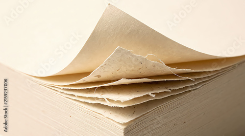 Stack of handmade textured paper sheets with rough edges in a soft light