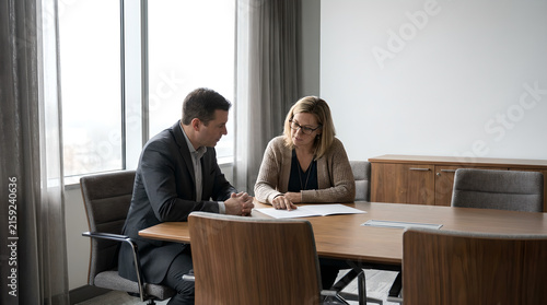 Professional business people sit at conference table reading documents in modern corporate office