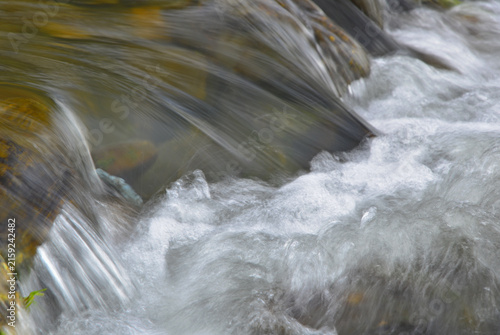 Water cycle: Flowing water in a mountain stream, creating a small rapid.
