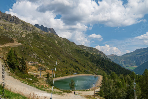 Turquoise mountain lake, rugged green slopes and cloud-filled sky in the French Alps near Chamonix.
