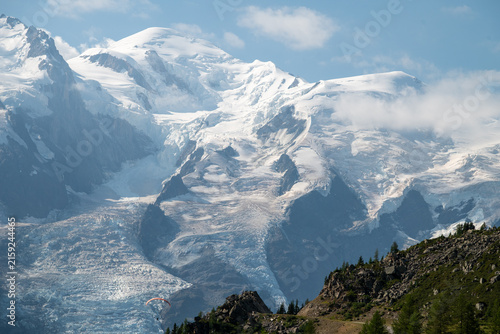 Majestic glacier-covered Mont Blanc massif rising above rugged green slopes in the French Alps during summer.