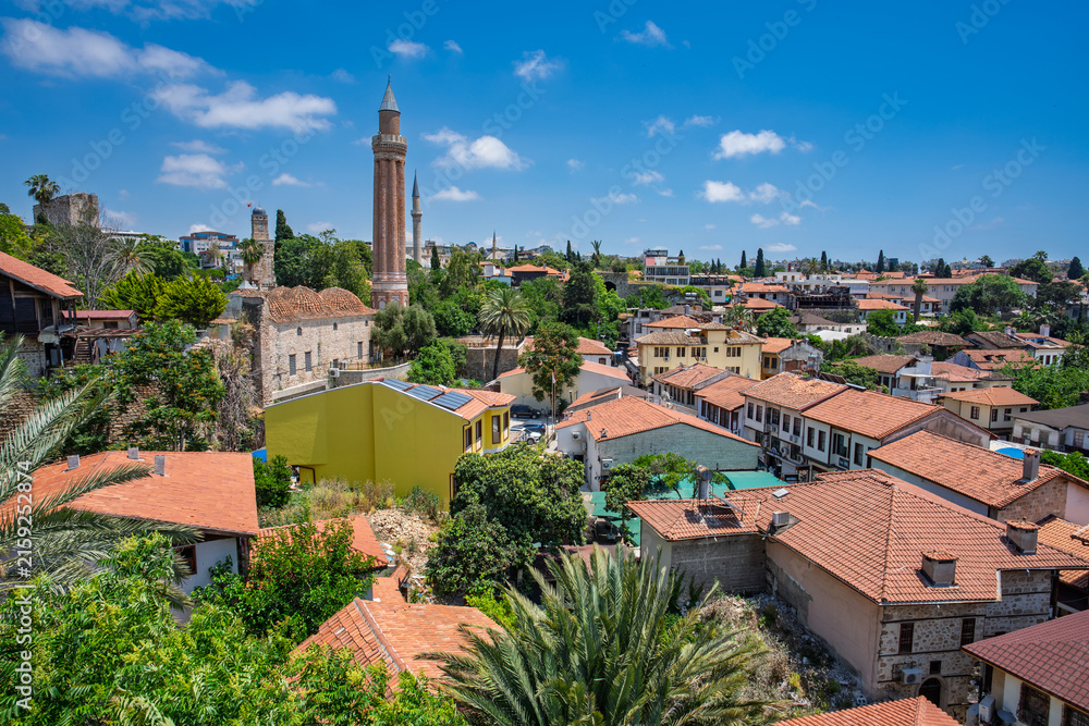 Fototapeta premium Panoramic Kaleici rooftops with a mosque minaret beneath summer clouds in Antalya, Turkey.
