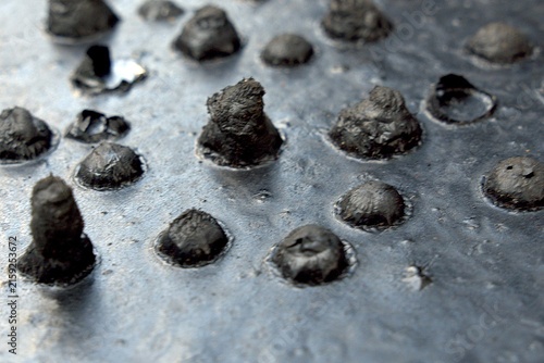 Obraz na plátně Close-up view of textured metal surface with protruding rivets and uneven patche