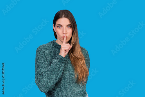 Fotografie Young woman making a silence gesture with finger on lips