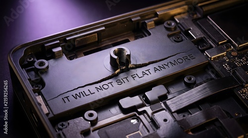 Macro view of a broken internal hardware component with the text IT WILL NOT SIT FLAT ANYMORE engraved on it, symbolizing irreparable damage and technical failure