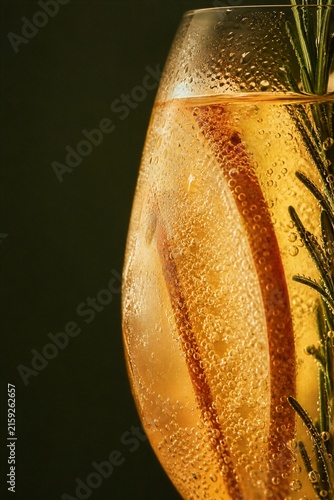 Sparkling nonalcoholic autumn cocktail with apple slice and rosemary in glass. Refreshing cold beverage with bubbles for harvest party celebration.