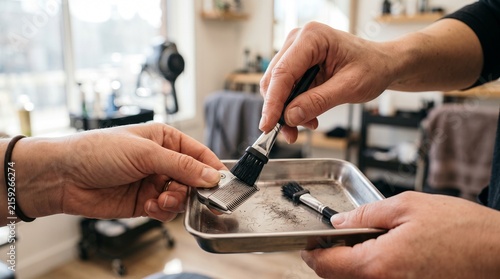 Barber cleaning hair clipper blades with a brush in a metal tray