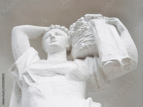 Quadro su tela Classical white plaster statue of a woman carrying a fruit basket, low angle vie