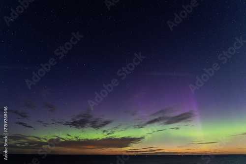 Aurora borealis with purple and green colors and shooting star over the sea in Estonia