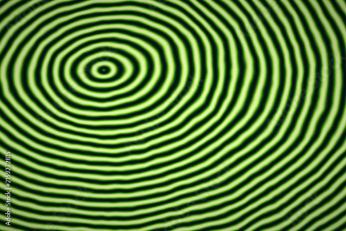 Abstract circular ripples pattern with vibrant green and black concentric rings creates hypnotic optic effect