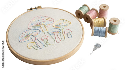 Embroidery hoop with mushroom pattern and colorful thread spools isolated on transparent background