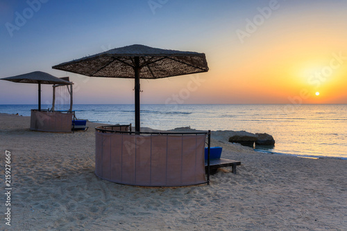 Sunbeds with umbrellas on the beach in Marsa Alam at sunrise, Egypt