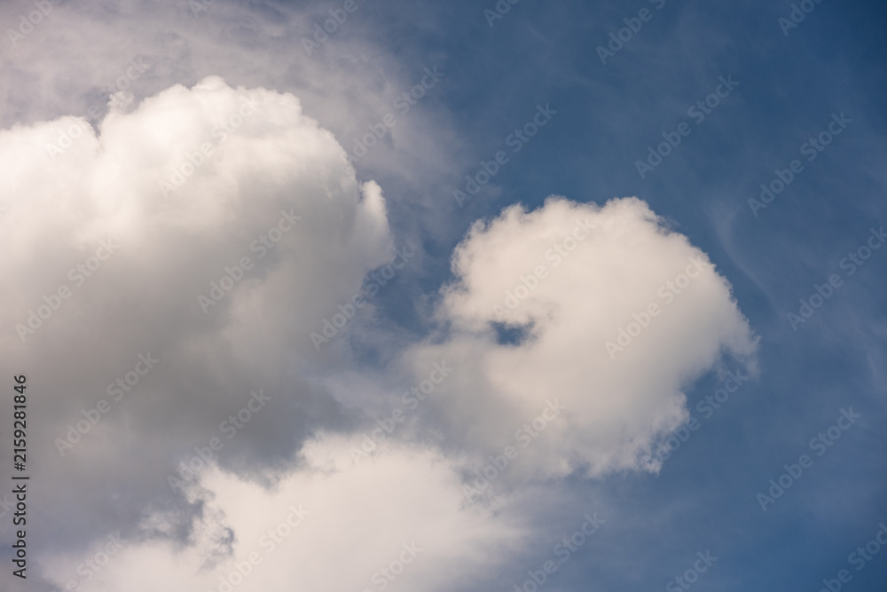 Obraz premium Fluffy white cumulus clouds in a dark blue sky, as a texture pattern nature background 