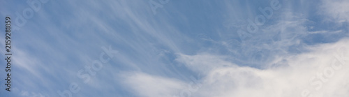 Wispy white cirrus uncinus clouds in a blue sky above cumulus clouds, as a texture pattern nature background
