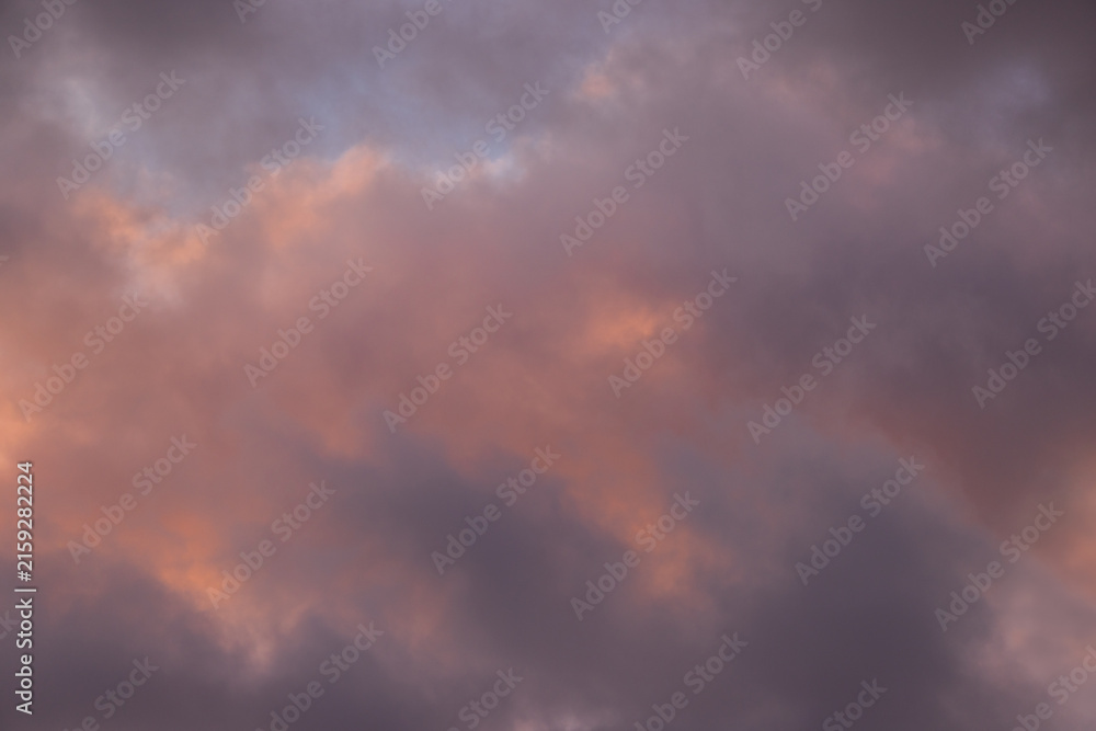 Fototapeta premium Moody dusk clouds with subtle pink and purple pastel tones illuminated by warm light. Dramatic atmospheric sky background perfect for artistic overlays, wallpapers, and creative design projects.