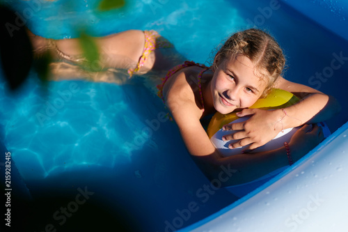 Принти на полотні Happy girl relaxing with a beach ball in a swimming pool