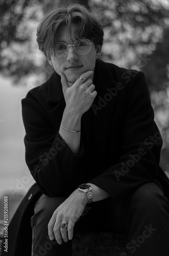 Cuadro en lienzo Black and white portrait of a handsome young man in a dark coat posing outdoors